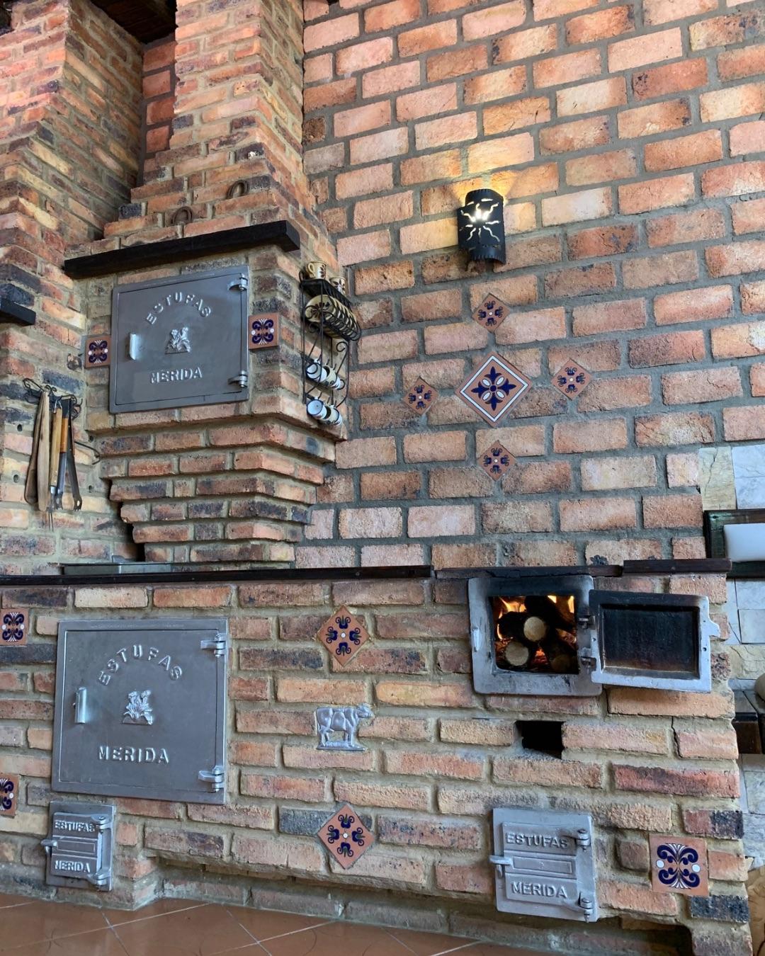 Fogón de ladrillo con fuego encendido y puertas de aluminio